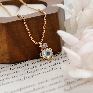 Dettaglio del ciondolo a fiore con topazio azzurro su catena dorata in stile vintage
