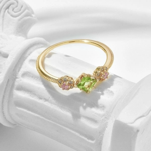 Gold plated S925 silver ring with peridot gemstone and floral accents on a pedestal