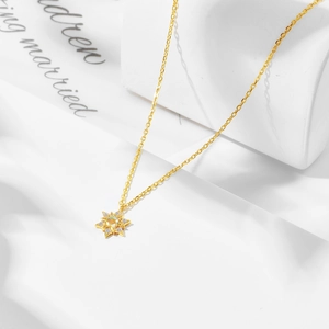 Makroaufnahme eines goldenen Sternenanhängers mit strahlendem Opal und kleinen Kristallen