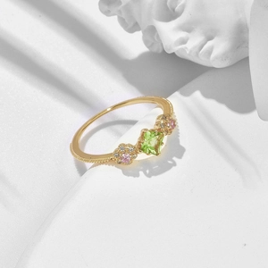Macro view of gold flower ring with square green gemstone and pink stone clusters