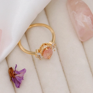 Macro detail of a gold strawberry quartz ring with zircon accents in a velvet box