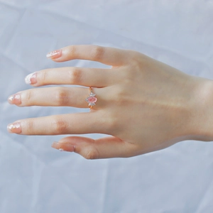 Close-up of pink strawberry quartz ring with zircon accents in rose gold on a finger