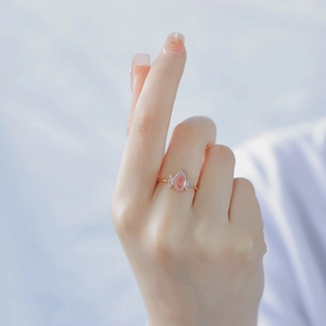 Detailed view of pink oval crystal ring with gold plating and white zircon accents