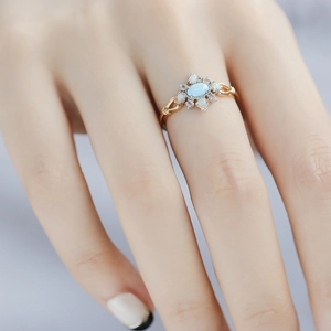 Close-up of a vintage-style ring with turquoise and opal stones on a model's finger