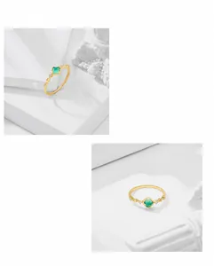 Detail view of square green gemstone ring with gold band and geometric diamond accents