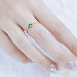 Gros plan d'une émeraude carrée sur une fine bague en argent plaqué or pour femmes