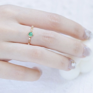 Détail d'une bague S925 dorée avec émeraude pain de sucre et accents de diamants géométriques