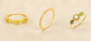 Vista detallada de tres anillos dorados vintage con piedras preciosas y texturas finas