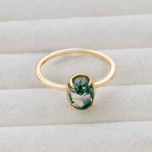 Macro view of natural moss agate stone with four-prong setting on gold-plated silver ring