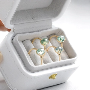 Macro shot of four gold-plated S925 silver rings with oval moss agate stones in a gray box