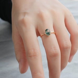 Detailed close-up of natural green agate moss ring in gold-plated silver on finger