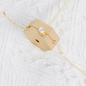 Detail of gold chain bracelet featuring moonstone and zircons on a golden stand