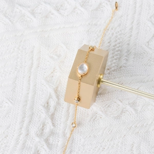 Elegant gold bracelet with white mother-of-pearl and crystal on geometric metal stand