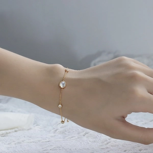 Close-up of gold chain bracelet with round clear crystal and adjustable bead on lace