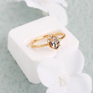 Detalle de un anillo dorado con cuarzo rutilado ovalado y grabados en la banda