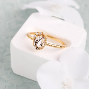 Elegante anillo de oro con cuarzo rutilado negro ovalado y diamantes sobre pétalos blancos