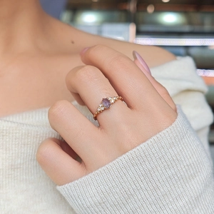 Detail of rose gold ring with oval purple gemstone and accent diamonds on model finger