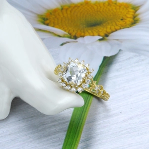Detailopname van een vergulde topaasring met een luxe halo en bewerkte opengewerkte band