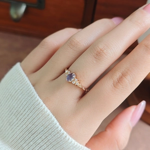 Close-up of gold silver ring with oval purple iolite and vintage vine engraving