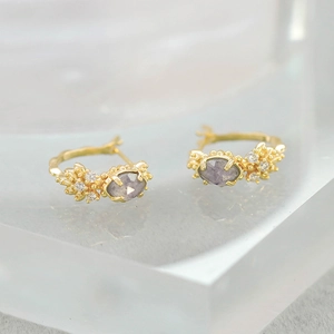 Detail of vintage gold-plated hoop earrings with oval gray stones and floral diamonds