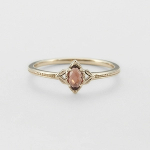 Detalle de anillo retro de oro con granate talla marquesa y bordes con acabado milgrain
