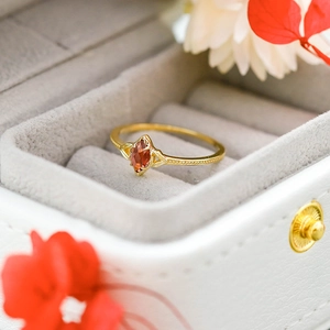 Vista macro de anillo de granate talla marquesa con textura de cuentas doradas en caja