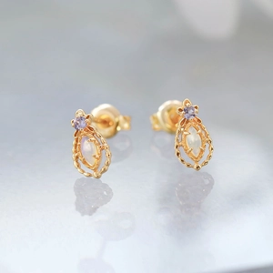Detail of vintage 14K gold plated earrings featuring opal and purple gemstone inlay
