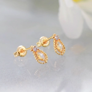 Macro view of vintage style gold earrings with marquise opal and purple gemstone detail