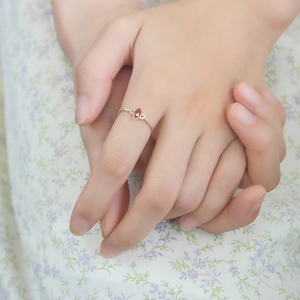 Detalle de anillo con granate corte marquesa y banda de cuentas sobre tela de flores