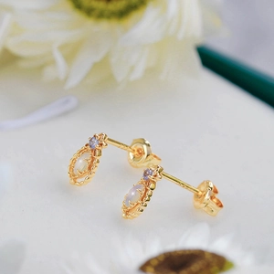 Close-up of vintage gold opal earrings with blue stone in intricate lace setting