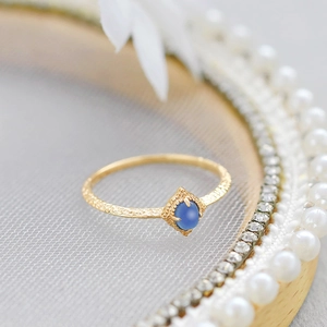 Macro view of vintage gold ring with hammered texture and blue oval gemstone