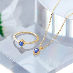 Artistic layout of blue gemstone jewelry set with gold hammered texture on acrylic blocks