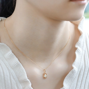 Close-up of 14K gold plated silver necklace with a delicate white opal pendant on model