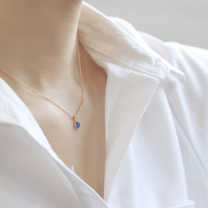 Rose gold necklace with vintage diamond window-inspired blue gemstone pendant on a model