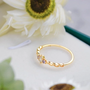 Macro shot of vintage 14K gold plated opal ring with purple zircon accents on floral background