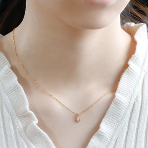Close-up of a teardrop opal pendant necklace with blue sapphire accent on a gold chain