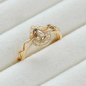 Detalle macro de un anillo dorado con gema marrón en forma de pera y circonitas blancas
