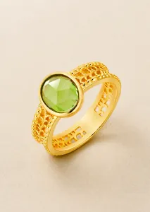 Detail of S925 silver 14k gold plated ring with oval green peridot and woven texture