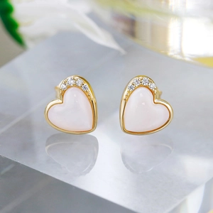 Macro detail of S925 silver 14K gold heart stud earrings with pink shell and zircons