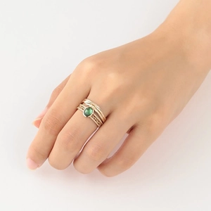 Detail eines Ring-Sets mit grünem ovalem Edelstein und hohlem goldenen Webdesign