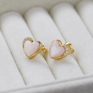 Macro detail of S925 silver heart stud earrings with pink shell and zircons in white gift box