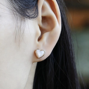 Close-up of heart-shaped 14K gold earring with pink shell and sparkling zircons on ear