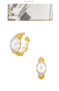 Détail de la boucle d'oreille dorée avec motif marguerite sur cristal blanc poli