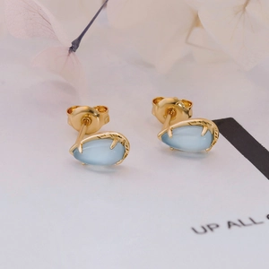 Detalle de pendientes en plata S925 bañada en oro con aguamarina y textura de rama natural