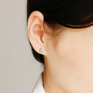 Primer plano de pendiente de lágrima en oro de 14k con piedra natural en la oreja del modelo