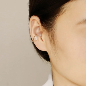 Détail d'une manchette d'oreille dorée avec cristal blanc ovale et bordure texturée fine