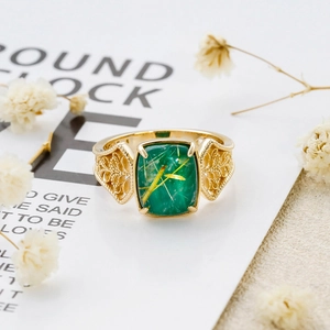 Macro detail of gold vintage ring featuring green stone and ornate floral carvings