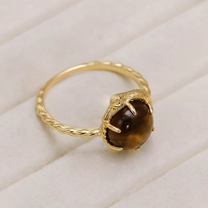 Primer plano de anillo garra de pájaro bañado en oro 14k con piedra ojo de gato café