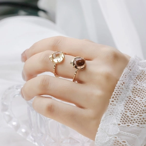 Detalle de anillos de banda dorada trenzada con piedras amarillas y marrones en la mano