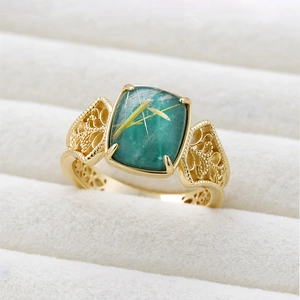 Macro detail of gold vintage ring featuring filigree work and a green rutilated quartz